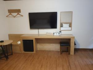 a wooden desk with a television on a wall at CF Motel in Jeju