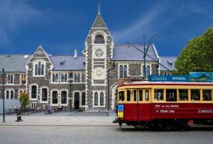 a bus in front of a building with a clock tower at Inner City Delight walk to Cathedral Square in Christchurch