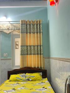 1 dormitorio con cama amarilla y espejo en Homestay Xuân Mai en Quang Ngai