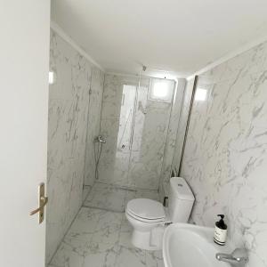 bagno bianco con servizi igienici e lavandino di R&T Apartments a Kallithea