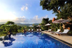 a swimming pool with chairs and umbrellas on a resort at Shanti Natural Panorama View Hotel in Singaraja