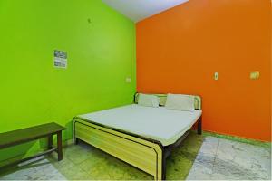 a small bed in a room with green and orange walls at OYO Vansh Guest House in Mathura