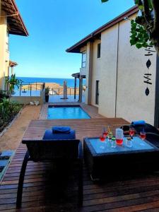 a wooden deck with two tables and a swimming pool at Sovereign Paradise - Unit 22 in KwaDukuza