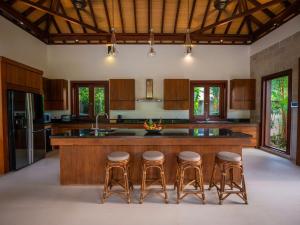 a kitchen with wooden cabinets and a island with bar stools at Baan Pinya Balinese Style Pool Villa in Krabi town