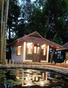 a small house with lights in front of a pond at Shantitheeram Ayurveda Lakeside Heritage Resort in Alleppey