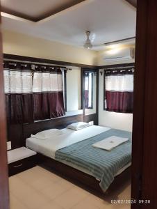 a bedroom with a large bed and windows at Hotel Grand Murud janjira in Murud