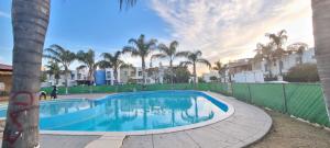 uma piscina com cerca e palmeiras em Casa con alberca a 15min poliforum y centro max Brisas em León