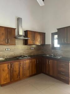 a large kitchen with wooden cabinets and a sink at Grace Holiday Bungalow in Haputale