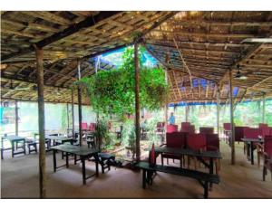 een restaurant met tafels en stoelen en een boom bij Tanshikar Spice Farm, Sanguem in Vichondrem