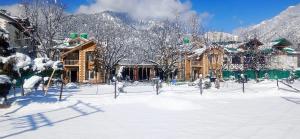a snow covered yard in front of a house at Lidder view resort in Pahalgām