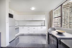 a kitchen with white cabinets and a table and a window at Oaks Sydney Hyde Park Suites in Sydney