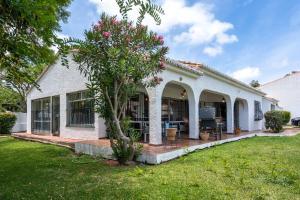 une maison blanche avec un arbre dans la cour dans l'établissement Family villa with garden next to the beach, à Mijas