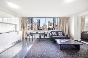 Oaks Sydney Hyde Park Suites في سيدني: غرفة معيشة مع أريكة وطاولة