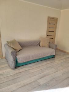 um sofá num quarto com piso em madeira em Квартира em Balkhash