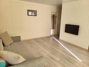 uma sala de estar com um sofá e uma televisão de ecrã plano em Квартира em Balkhash
