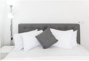 Cama blanca con almohadas blancas y almohada gris en Riviera residence by T T P, en Accra 9 fotos más