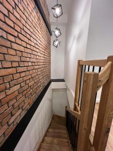 a brick wall next to a staircase with a wooden rail at Kolejowa 4 Boutique Apartment in Nowa Ruda