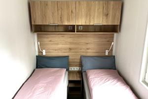 2 camas en una pequeña habitación contigua en Ostseecamp Ferienhaus "Lüttche Hus" en Scharbeutz