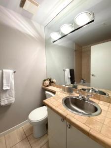 een badkamer met een wastafel, een toilet en een spiegel bij LLT Richard in Vancouver