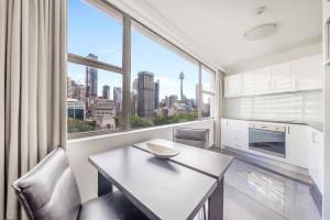 a kitchen with a table and chairs and a large window at Oaks Sydney Hyde Park Suites in Sydney