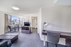 an apartment living room with a desk and a table at Oaks Sydney Hyde Park Suites in Sydney