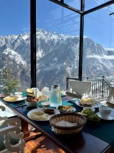 a table with food on it with a view of mountains at Faraway Cottages, Auli in Joshīmath