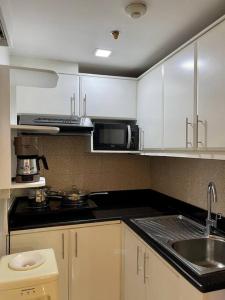 a kitchen with white cabinets and a sink and a microwave at Homey & Stylish 2BR @ Burgos Circle, BGC, Taguig in Manila