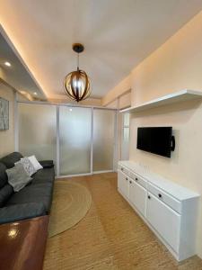 a living room with a couch and a flat screen tv at Homey & Stylish 2BR @ Burgos Circle, BGC, Taguig in Manila