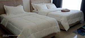 duas camas com cobertores brancos e almofadas num quarto em RJ STUDIO APARTMENT 2- Hotel Mutiara em Gua Musang
