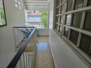 a hallway with a staircase in a building with windows at Newly remodeled 2nd Floor Unit, 5 BR in Mayaguez