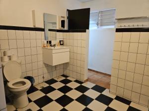 a bathroom with a toilet and a checkered floor at Newly remodeled 2nd Floor Unit, 5 BR in Mayaguez