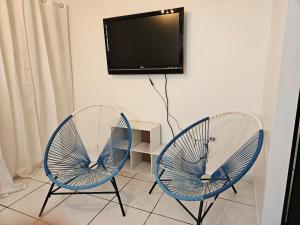 two blue chairs sitting next to a tv on a wall at Newly remodeled 2nd Floor Unit, 5 BR in Mayaguez