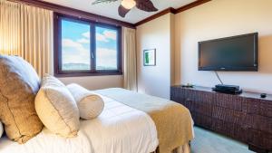a bedroom with a bed with a flat screen tv at Ko Olina Beach Villas O704 in Kapolei