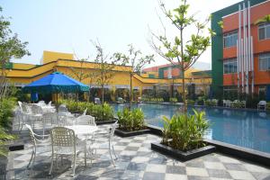 un patio avec des tables et des chaises à côté d'une piscine dans l'établissement Mayfair World Cup Village, à Rourkela