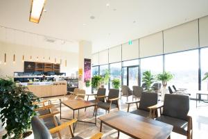 una cafetería con mesas, sillas y ventanas en Gangjin K-Stay Tourist Hotel en Kangjin