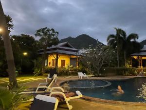 a villa with a swimming pool in front of a house at Grand Manita Beach Resort in Lamai