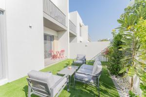d'une terrasse avec des chaises et une table sur la pelouse. dans l'établissement Cosy Luxury villa Tilal Alghaf, à Dubaï