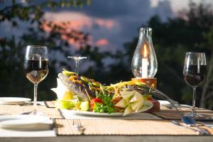 a table with a plate of food and two glasses of wine at The Horizon Hill Top Villa in Unawatuna