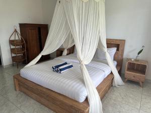 a bedroom with a canopy bed with towels on it at Azona Greens Uluwatu in Uluwatu