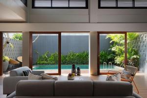 a living room with two couches and a pool at The Kemilau Hotel & Villa Canggu Bali in Canggu