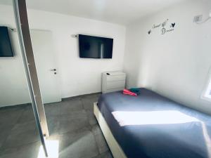 een kleine slaapkamer met een bed en een televisie bij Beautiful apartment near Tel Aviv in Bat Yam