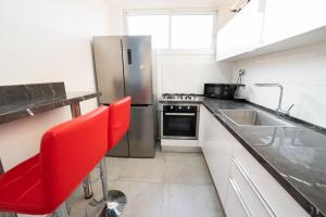 een keuken met een roestvrijstalen koelkast en een rode stoel bij Beautiful apartment near Tel Aviv in Bat Yam