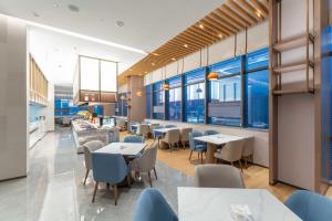 ein Restaurant mit Tischen, Stühlen und Fenstern in der Unterkunft Holiday Inn Express Bazhong Center, an IHG Hotel in Bazhong