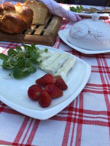 un plato de queso y fresas en una mesa en Tornácos Tanya Vendégház*** és Gasztroporta, en Kiskunmajsa