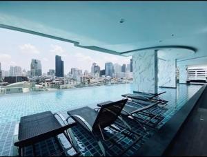 a swimming pool with chairs and a view of a city at Supalai Bangkok in Bangkok