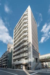 un edificio alto y blanco con un cielo en 谷町君HOTEL 心斎橋東32, en Osaka