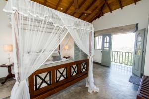 a bedroom with a bed with mosquito netting at The Horizon Hill Top Villa in Unawatuna