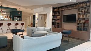 une bibliothèque avec un canapé, des chaises et une télévision dans l'établissement Holiday Inn Express Lille Centre, an IHG Hotel, à Lille