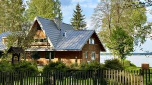 uma casa de madeira com uma cerca em frente em Lustro Wody em Osiek