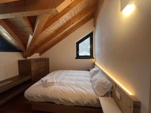 1 dormitorio con 1 cama blanca en el ático en Casa Giuliana con SkiBus Gratis, en Aprica